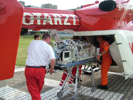Rettungsassistenten beim Einladen eines Inkubators in einen Rettungshubschrauber