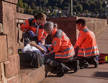Drei Sanitäter versorgen einen Patienten auf einer Brücke