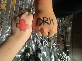 Hände zweier Schüler, bemalt mit einem roten Kreut und dem Schriftzug DRK
