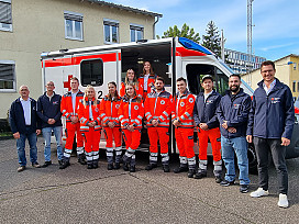 Gruppenbild: 8 angehende NotfallsanitäterInnen vor einem Rettungswagen mit ihren Ausbildern