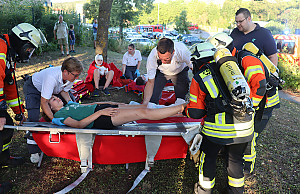 Mehrere Sanitäter-innen legen eine Verletzte auf eine Trage