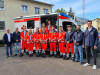 Gruppenbild: 8 angehende NotfallsanitäterInnen vor einem Rettungswagen mit ihren Ausbildern