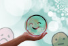 Eine Hand hält eine Kugel in Form eines Smileys hoch