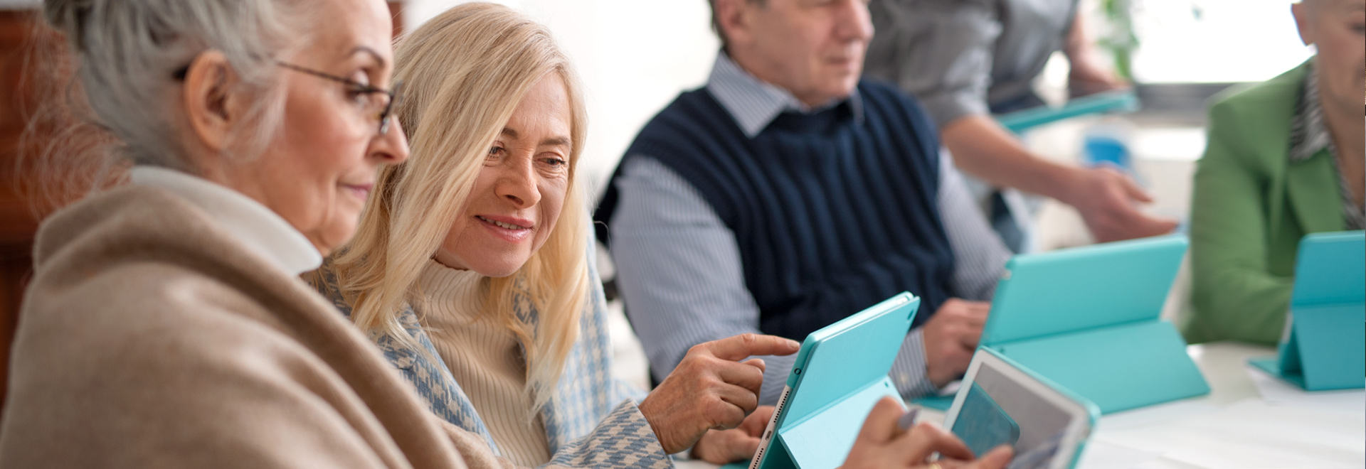 verschiedene ältere Menschen bei einer Schulung mit Tablets