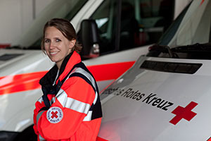 Eine Rettungssanitäterin und ein Rettungssanitäter vor einem Rettungswagen