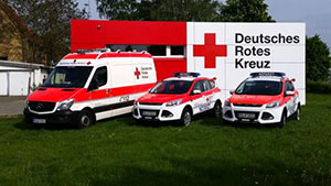 Drei neue Fahrzeuge vor einem Gebäude des Deutschen Roten Kreuzes