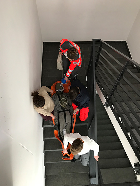 Rettungssanitaeter tragen einen Verletzten durch ein Treppenhaus