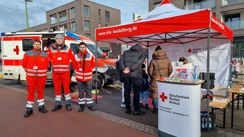 DRK-Mitarbeiter am Stand des DRK Rhein-Neckar/Heidelberg vor einem Rettungswagen
