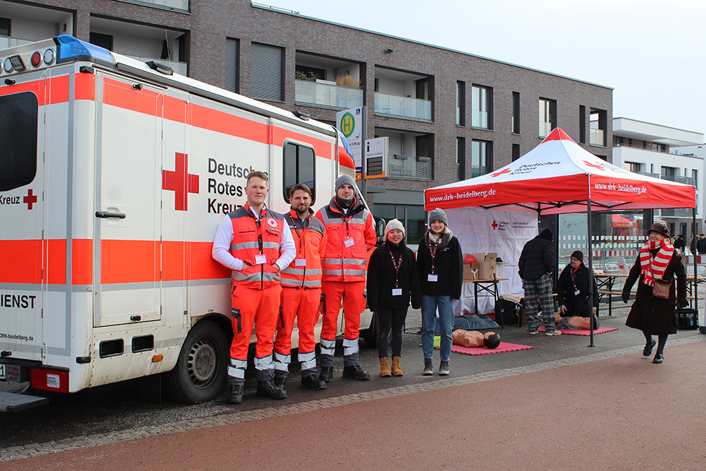 DRK-Mitarbeiter am Stand des DRK Rhein-Neckar Heidelberg vor einem Rettungswagen