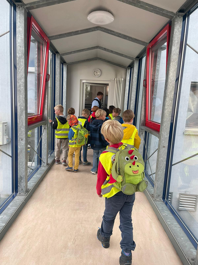 Kinder in einem Flur mit einem Polizisten