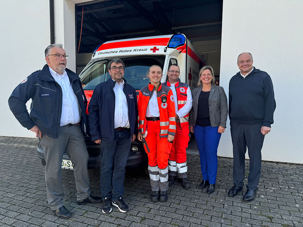 Gruppenbild - Vertreter-innen des DRK vor einem Rettungswagen