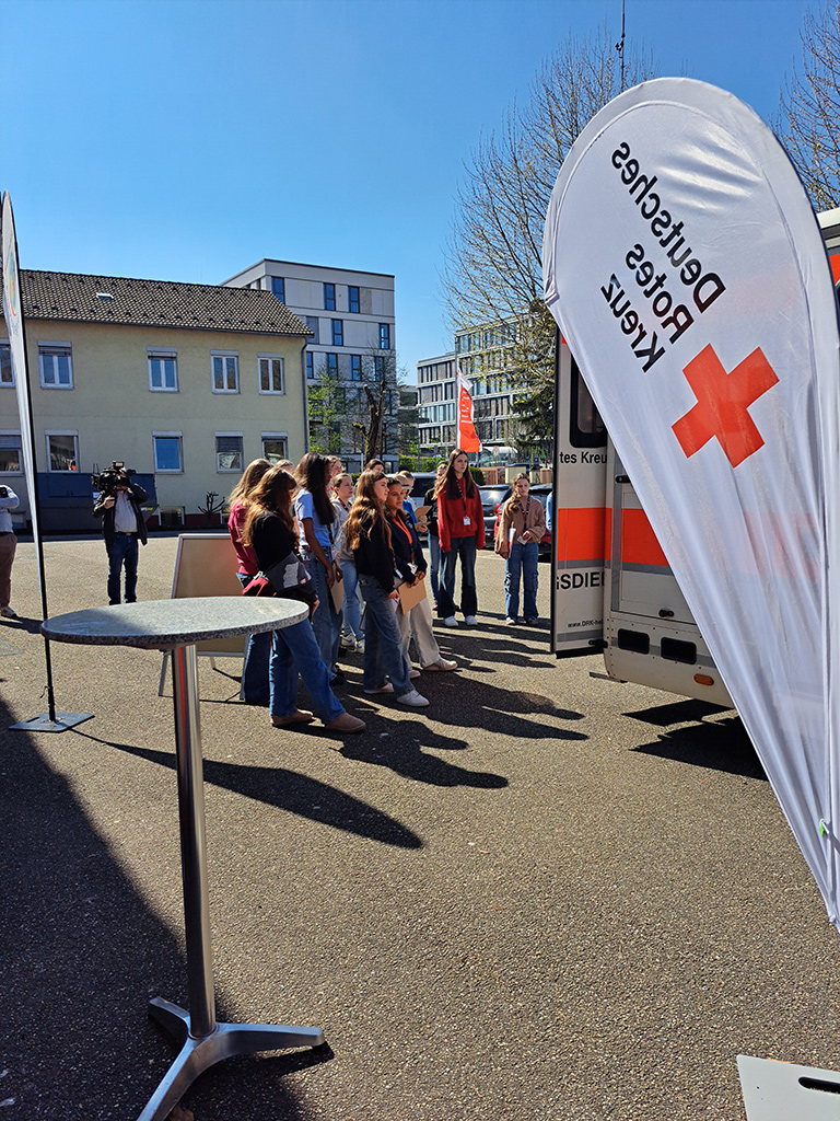 Mädchen und Jungen stehen vor einem Retungswagen