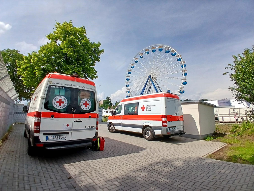 Zwei geparkte DRK-Fahrzeuge, im Hintergrund ein Riesenrad