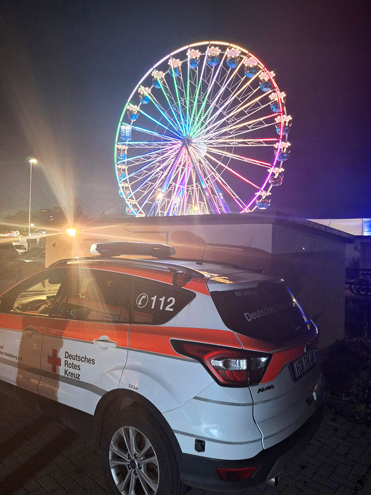 DRK-Fahrzeug im nächtlichen Einsatz, im Hintergrund das beleuchtete Riesenrad