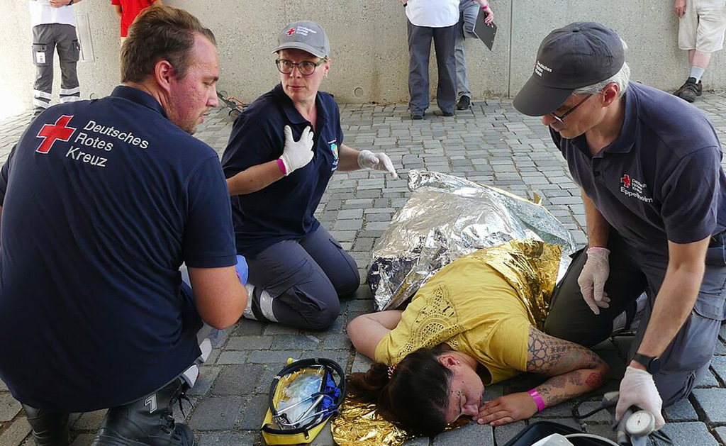 Übung: Rettungssanitäter versorgen eine verletzte Person, die auf dem Boden liegt