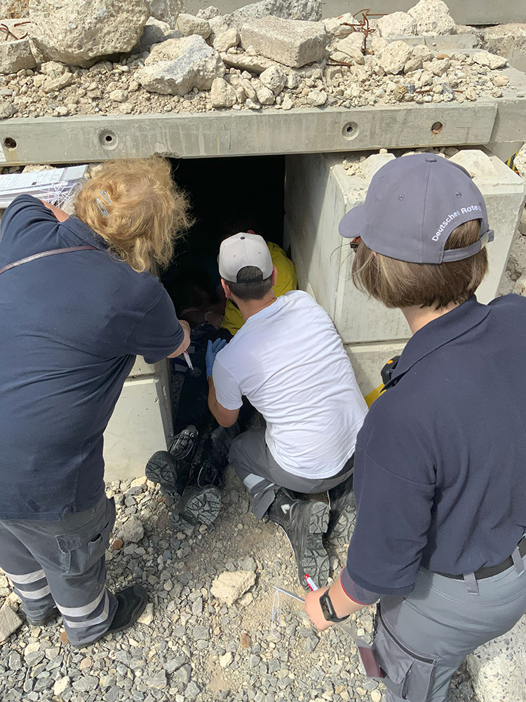 Drei Personen suchen nach verschütteten Personen in einer Gebäudeöffnung