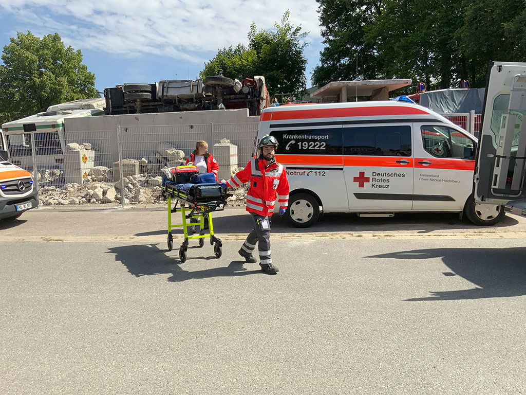 Sanitäter schieben eine Trage über das Gelände