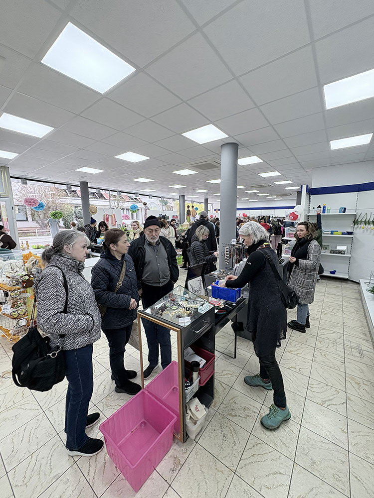 Kundinnen und Kunden stehen vor einer Vitrine und Tischen mit Schmuck