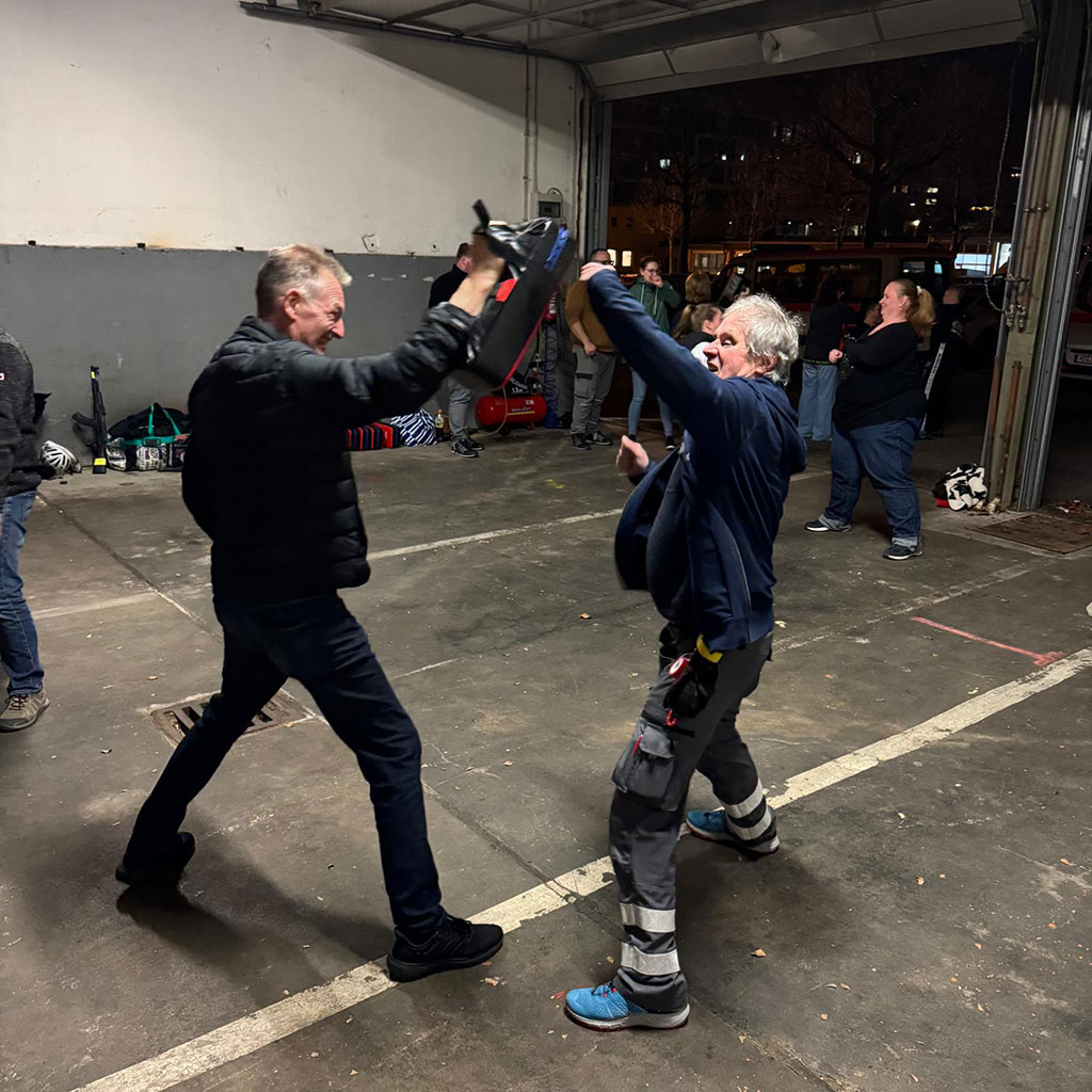 Zwei Männer üben Selbstverteidigung: ein Mann wehrt mit der Faust einen Angriff eines anderen Mannes ab