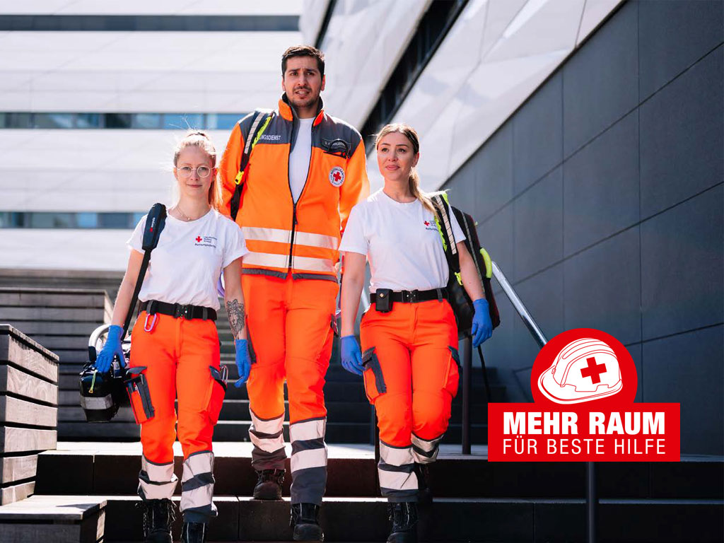 Drei Rettungsdienstmitarbeitende laufen eine Treppe hinunter; daneben ein Logo mit der Beschriftung Mehr Raum für beste Hilfe