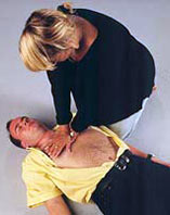 Frau bei der Herzmassage bei einem auf dem Boden liegenden Mann