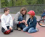 Frau hilft zwei Kindern nach Sturz vom Fahrrad