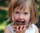 Kleines Mädchen, das gerade ein Brötchen mit Aufstrich isst