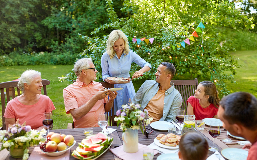 Geburtstagsfeier im Garten; eine Frau verteilt an die Gäste Kuchen