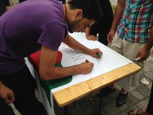 Teilnehmer malt ein Plakat mit einem Schriftzug