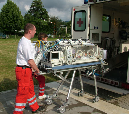 Rettungsassistenten beim Einladen eines Inkubators (Brutkasten) in den Rettungswagen