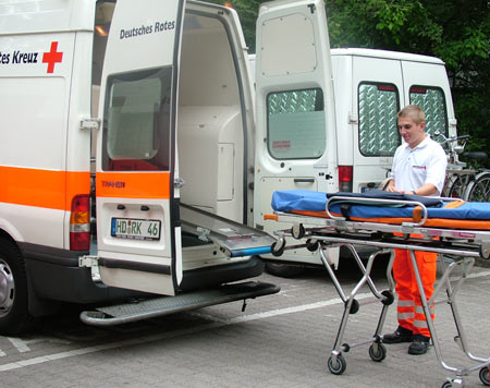 Rettungsdienst-Mitarbeiter mit Trage am Krankenwagen