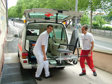 Mitarbeiter beim Ausladen eines Tragestuhls aus einem Krankentransportwagen