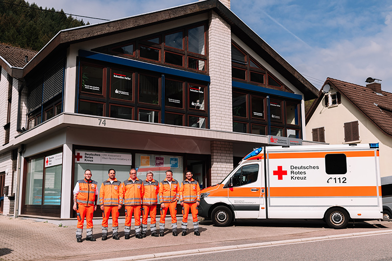 Team der Rettungswache Schönau neben einem Rettungswagen vor der Rettungswache