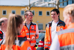 Mehrere DRK-Mitarbeiter unterhalten sich im Freien