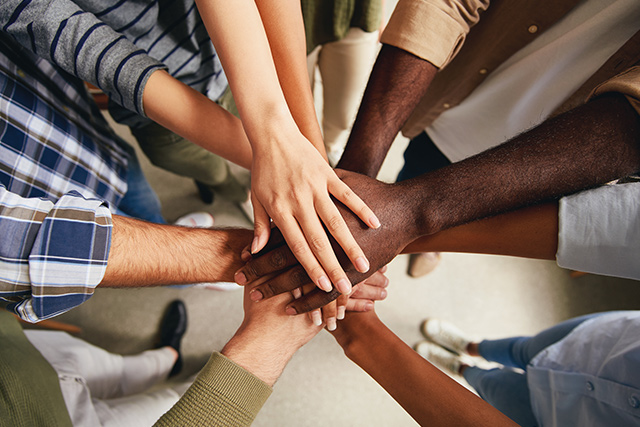 Zur Antidiskriminierungsstelle Mehrere Personen mit verschiedener Hautfarbe legen ihre Hände übereinander