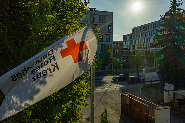 Zur Kontakt-Seite DRK-Fahne vor einem Baum