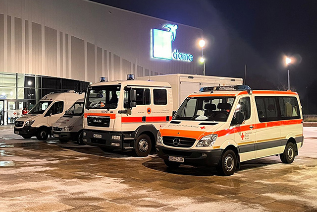 Informationen zu den Einsatzeinheiten DRK-Rettungswagen am Abend auf einem Parkplatz vor einer Halle