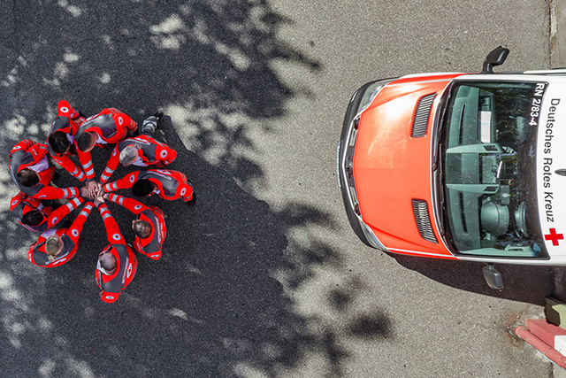 Was wir als Arbeitgeber bieten DRK Mitarbeiter im Kreis fassen sich im Mittelpunkt an den Händen